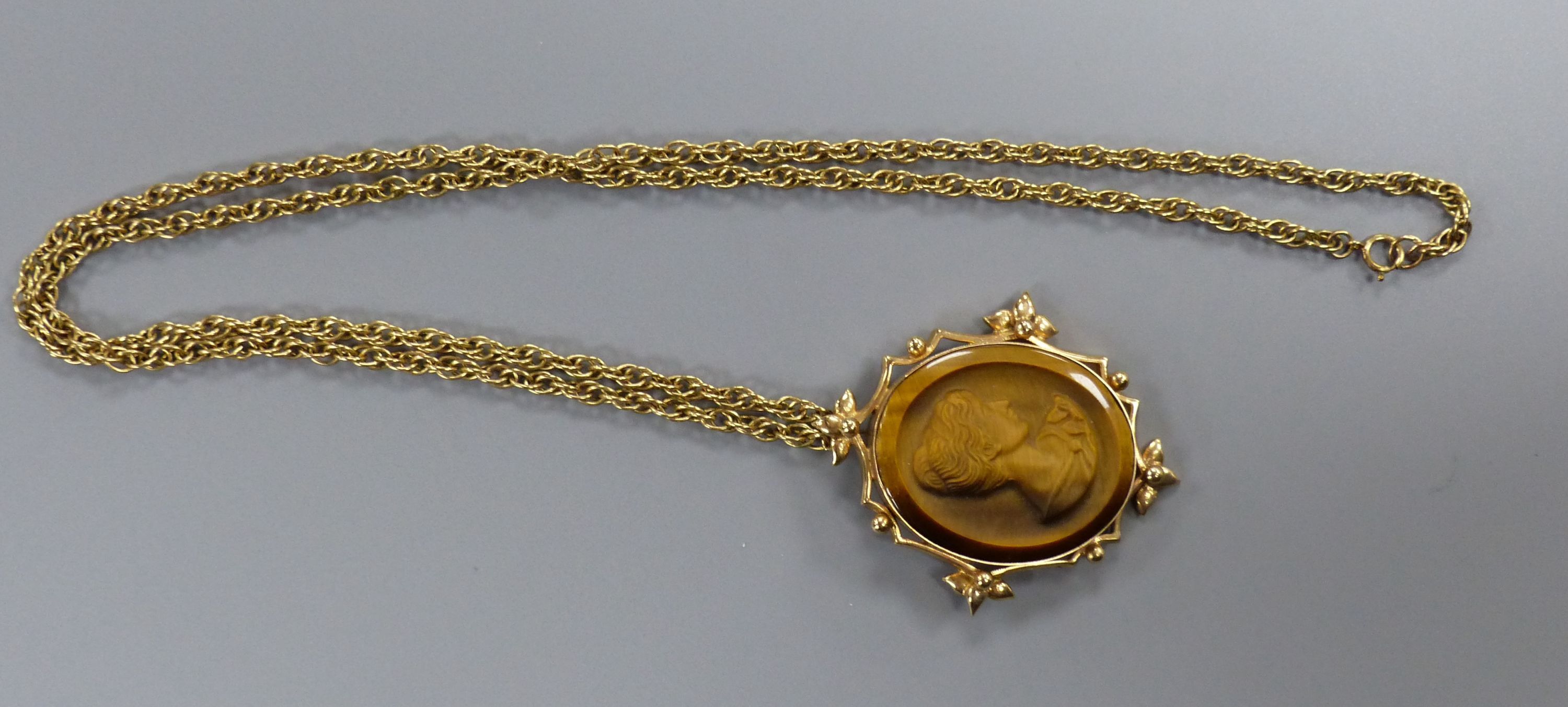 A yellow metal mounted tiger's eye quartz oval pendant, on a 9ct chain